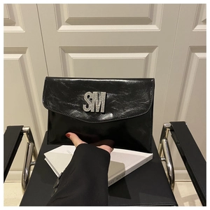 Detail of black glossy envelope clutch featuring silver rhinestone SM logo embellishment