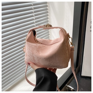 Detail of light pink faux crocodile skin texture and gold metal buckle on hobo bag