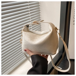 Detail of white snake-pattern embossed texture and gold hardware on the handbag