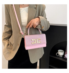 Detail of pink glitter crossbody bag with gold logo and elegant curved top handle