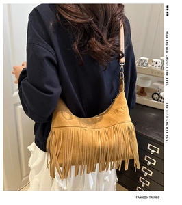 Detail of vintage suede hobo bag featuring dense bohemian fringes in ginger yellow