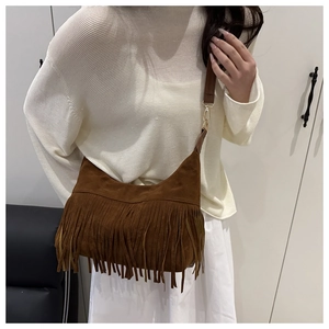 Detail of brown suede hobo bag featuring long bohemian tassels and golden metal hooks
