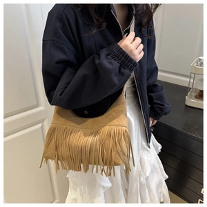Detail of caramel suede crossbody bag with long fringes and vintage crescent design