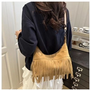 Detail of tan faux suede hobo bag featuring long hanging tassels and slim shoulder strap