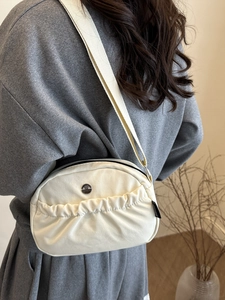 Chic beige crossbody bag with pleated detail and adjustable wide woven strap on model