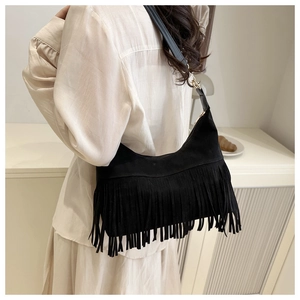 Detail of black crescent shoulder bag with long fringe and gold metal buckles