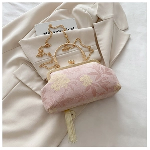 Dettaglio borsa a conchiglia in jacquard rosa con fiori dorati e nappa avorio
