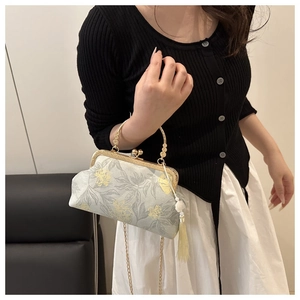 Detail of elegant satin square bag featuring yellow floral embroidery and pearl tassel charm
