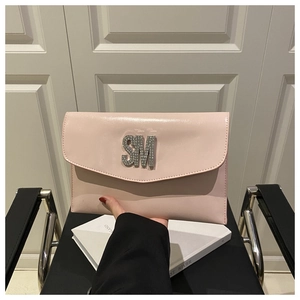 Detail view of pink patent leather envelope clutch featuring rhinestone SM logo