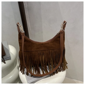 Detail of dark brown suede hobo bag with long fringes and golden hardware on a white stand