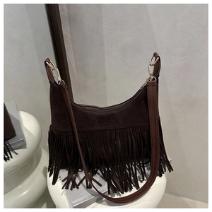 Detail of dark brown suede crossbody bag with long fringes and gold metal hardware