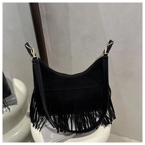Detailed view of black suede hobo bag with long fringe tassels and golden metal hooks