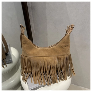 Detailed view of brown suede shoulder bag with bohemian long fringe and gold metal hardware