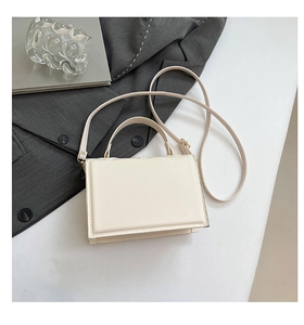 Flat lay of cream crossbody bag with gold hardware on neutral background