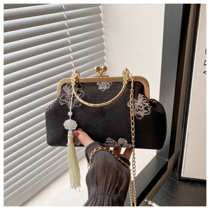Detail of vintage black velvet bag with floral embroidery and golden ring handle