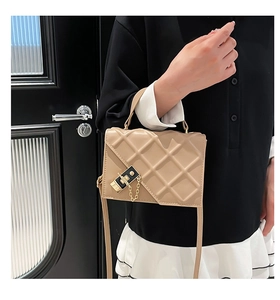 Detail of beige quilted shoulder bag featuring gold chain and luxury square buckle clasp