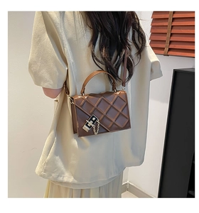 Detail of coffee brown quilted crossbody bag with metal buckle and chain accent