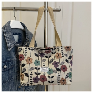 Detail of beige canvas tote bag with retro floral print and woven handles on a hanger