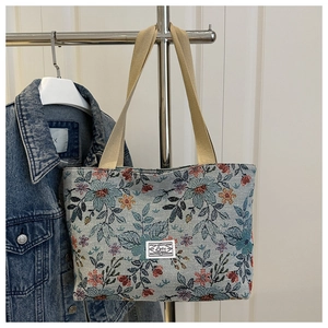 Detail of vintage floral jacquard tote bag with woven handles and Lotus logo tag