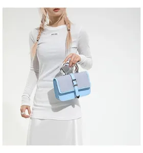 Detail of light blue leather handbag featuring a unique circular silver metal handle