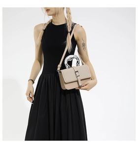 Detail of elegant beige crossbody bag with unique silver metallic handle and heart charm