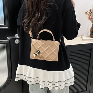 Khaki quilted square handbag with chain lock detail shown in a modern interior setting