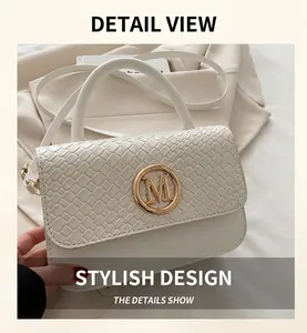 Détail du sac à main blanc avec fermoir M doré et rabat à texture tressée élégante