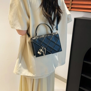 Minimalist black quilted crossbody bag with gold chain and handle shown on a model