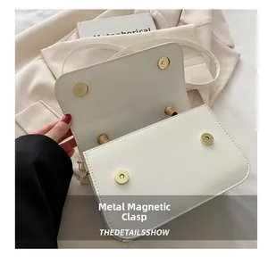 Gros plan détaillé du sac bandoulière blanc avec sa boucle magnétique dorée élégante