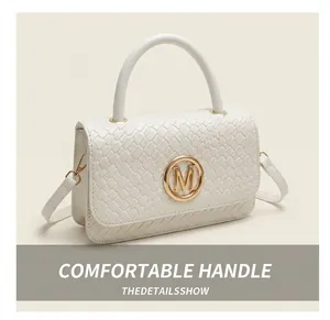Détail du sac à main blanc en cuir tressé avec boucle dorée M sur blazer beige