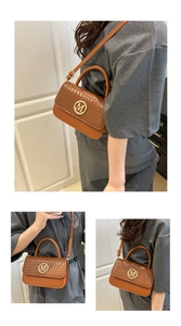 Detail view of orange-brown crossbody bag with woven flap and golden M logo hardware