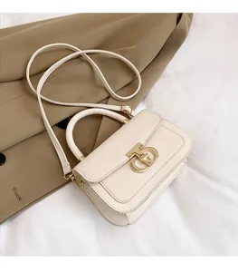 Detail view of cream crossbody bag featuring golden T-bar lock and lychee leather texture