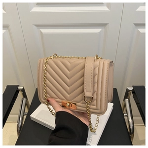 Detail of beige quilted shoulder bag with gold square lock and metallic chain strap