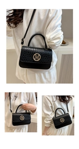 Detail of black mini square bag featuring checkerboard texture and golden M letter logo