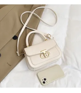 Detail showing cream vintage flap bag with gold metal buckle on beige trench coat