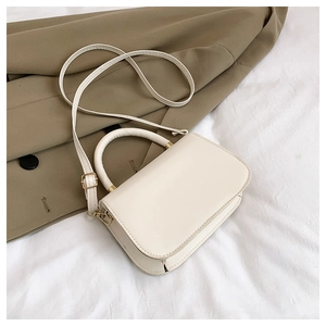 Détail d'un sac à main blanc structuré avec poignée supérieure et ferrures dorées chic