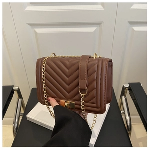 Detail of dark brown V-quilted faux leather bag with gold chain strap and twist lock