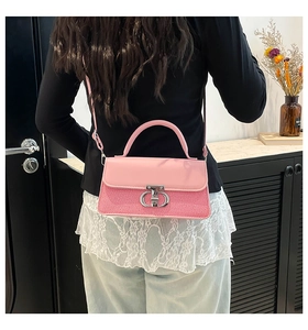 Detail view of pink patchwork handbag with silver metal buckle worn by a model