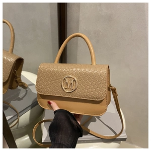 Détail du sac beige avec rabat tissé et logo M en métal doré sur le devant