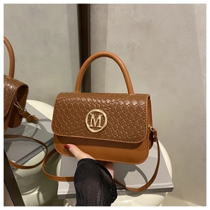 Détail du sac à main vintage en cuir marron avec texture tressée et boucle logo M doré
