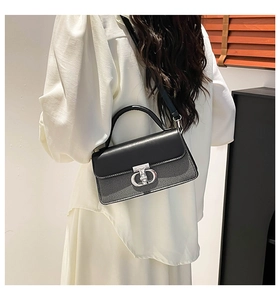 Detail view of the silver double-ring metal buckle on a black leather crossbody handbag