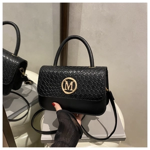 Détail d'un sac à rabat en cuir tressé noir avec logo M doré et reflet de miroir