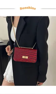 Detail of red crocodile texture patent leather bag with gold chain and metal twist lock