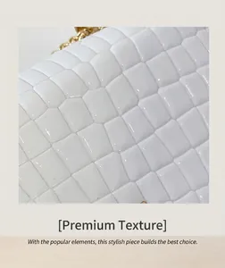 Close-up of white crocodile pattern patent leather with elegant gold chain strap