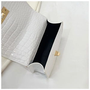 Detail of white crocodile pattern patent leather bag with gold buckle and black lining