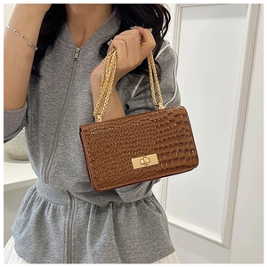 Close-up of brown crocodile texture leather bag featuring gold chain and square lock