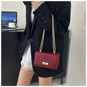 Close-up of crocodile textured burgundy crossbody bag with gold chain strap and metal lock