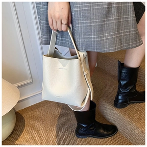 Détail du sac seau beige en cuir grainé avec une bandoulière amovible et poignée