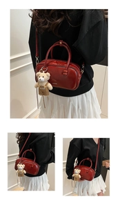 Detail of dark red glossy Boston bag with plush bear charm and white logo print