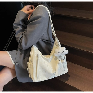 Detail of off-white pleated shoulder bag with cute cloud plush charm on a model